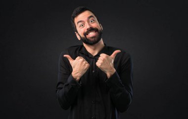 Siyah arka plan üzerine başparmak ile sakallı yakışıklı adam