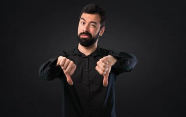 Siyah arka plan üzerine kötü sinyal yapma sakallı yakışıklı adam