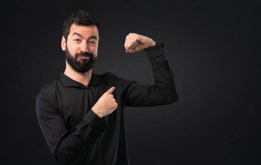 Siyah arka plan üzerinde güçlü bir jest yapma sakallı yakışıklı adam