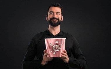Popcorns siyah arka plan üzerine yemek sakallı yakışıklı adam