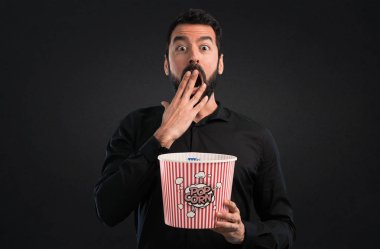 Popcorns siyah arka plan üzerine yemek sakallı yakışıklı adam