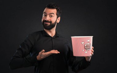 Popcorns siyah arka plan üzerine yemek sakallı yakışıklı adam