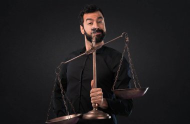 Siyah arka plan üzerine bir denge holding sakallı yakışıklı adam