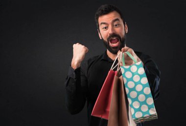 Siyah arka plan üzerine alışveriş çantası ile sakallı yakışıklı adam