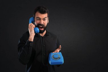 Siyah arka plan üzerine konuşmak için vintage telefon sakallı yakışıklı adam