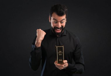 Siyah zemin üzerine altın külçe ile sakallı yakışıklı adam