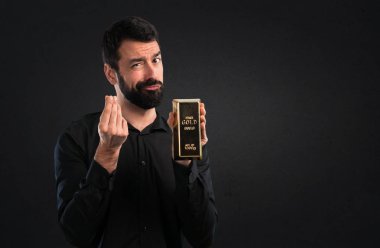 Siyah zemin üzerine altın külçe ile sakallı yakışıklı adam