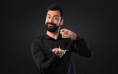 Siyah arka plan üzerine bir oyuncak uçak holding sakallı yakışıklı adam