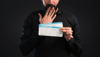 Siyah arka plan üzerine uçak bileti tutarak sakallı yakışıklı adam