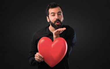 Siyah arka plan üzerine tutmak bir kalp oyuncak sakallı yakışıklı adam