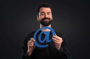Nokta com siyah arka plan üzerine simgesi tutan sakallı yakışıklı adam