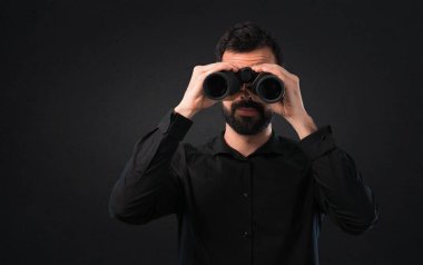 Siyah arka plan üzerine dürbünlü sakallı yakışıklı adam