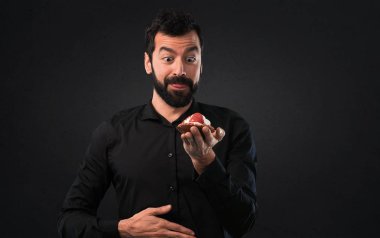 Siyah arka plan üzerine pasta ile sakallı yakışıklı adam