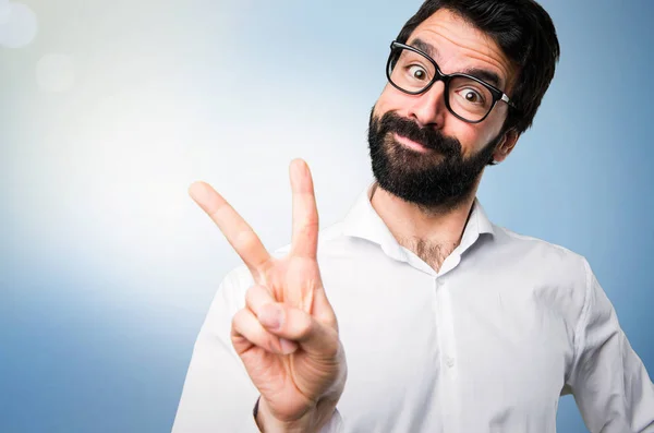 Stilig Man Med Glasögon Gör Seger Gest Blå Bakgrund — Stockfoto