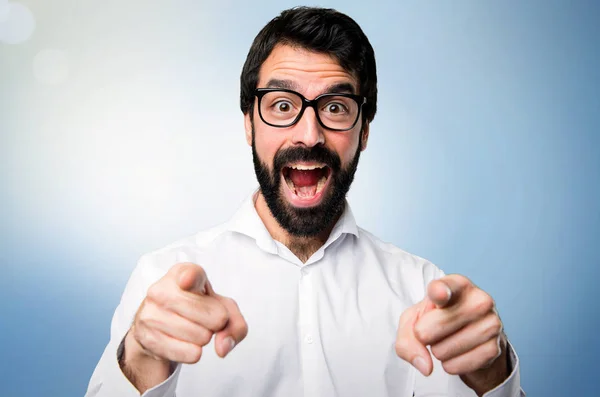 Hombre Guapo Con Gafas Apuntando Frente Sobre Fondo Azul —  Fotos de Stock