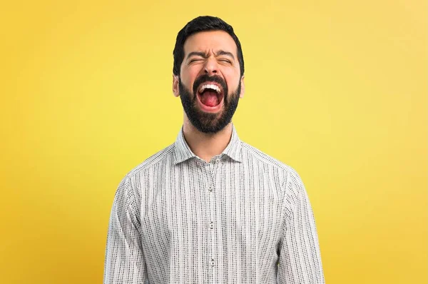 Handsome man with beard shouting with mouth wide open