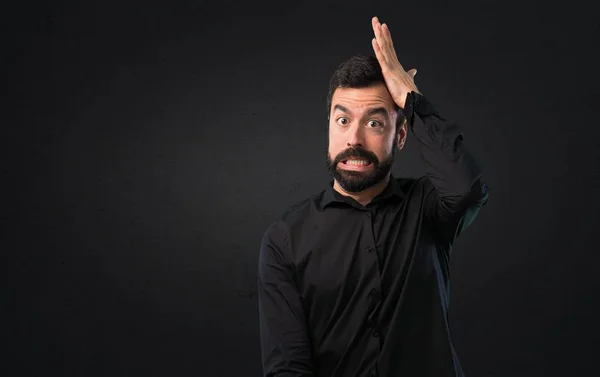 Handsome man with beard having doubts on black background