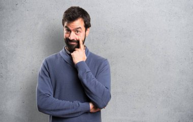 Bir şey dokulu arka plan üzerinde gösterilen sakallı yakışıklı esmer adam