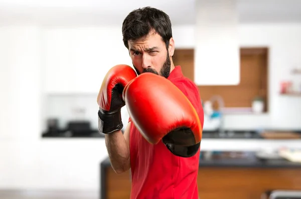 Handsome man with boxing gloves inside house