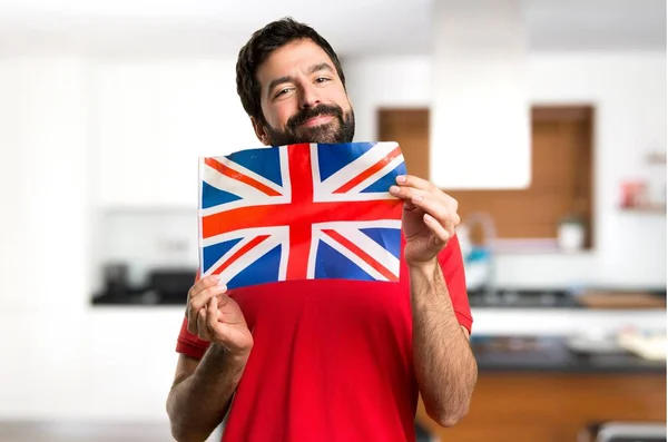 Szczęśliwy Przystojny Mężczyzna Trzyma Flagę Wielkiej Brytanii Wewnątrz Domu — Zdjęcie stockowe