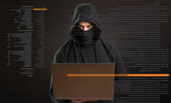 Hacker with his computer on dark background