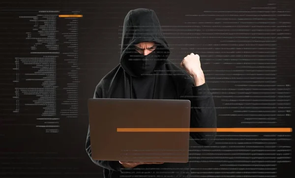 Lucky hacker with his computer on dark background