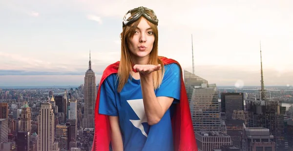 Pretty superhero girl sending a kiss in a skyscraper city