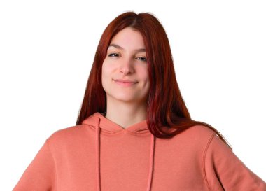 Silah, kalça ile poz ve önüne izole beyaz arka plan üzerinde seyir gülüyor pembe kazak ile genç Kızıl saçlı kız