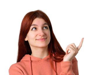 Harika bir fikir işaret parmağı ile işaret ve izole beyaz arka plan üzerinde ararken pembe kazak ile genç Kızıl saçlı kız