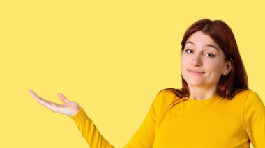 Genç Kızıl saçlı kız sarı kazak önemsiz yapma ve şüphe ile jest sırasında kaldırma izole sarı arka plan üzerinde omuz ve ellerde