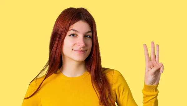 分離された黄色の背景に指で黄色いセーターを着て幸せとカウント で若い赤毛の女の子 — ストック写真