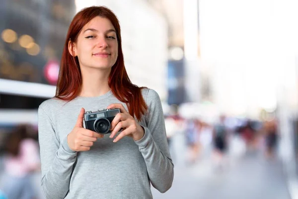 Bir Kamera Odaklanmamış Arka Planda Tutan Genç Kızıl Saçlı Kız — Stok fotoğraf