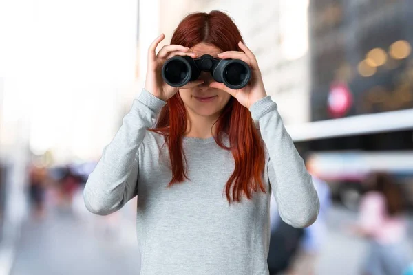 Chica Pelirroja Joven Busca Algo Distancia Con Prismáticos Sobre Fondo — Foto de Stock