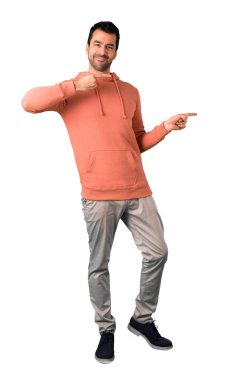 Tam erkek vücudunda parmak tarafına işaret ve izole beyaz arka plan üzerinde gülümseyen bir ürün sunan pembe bir kazak