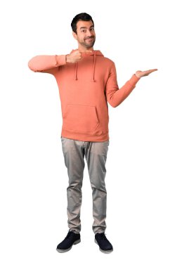 Adam tam vücut kopya alanı izole beyaz zemin üzerinde bir reklam eklemek için avuç hayali tutan bir pembe kazak içinde