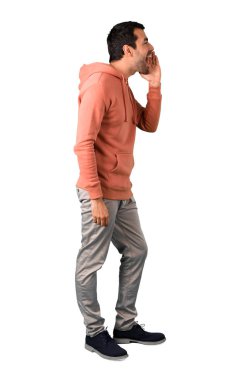 Adam tam vücut içinde geniş açık ağız ile bağırarak ve izole beyaz arka planda bir şey ilan pembe bir kazak