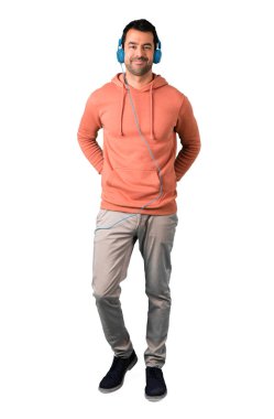 Adam tam vücut içinde izole beyaz arka plan üzerinde kulaklık ile müzik dinlemek bir pembe kazak