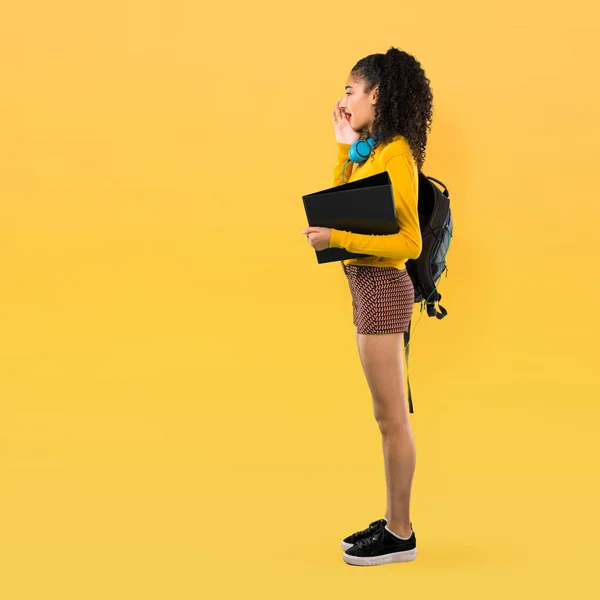 巻き毛で口を開けて叫びと黄色の背景で何かを発表の 代学生の女の子の完全なボディ — ストック写真