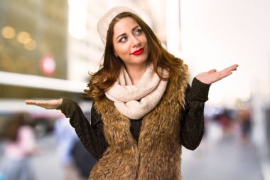 Önemsiz jest yapmak odaklanmamış arka plan üzerinde kış kıyafetleri ile kız