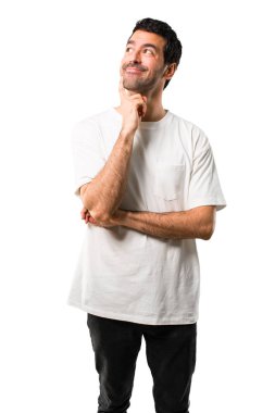 Genç adamla ayakta ve izole beyaz arka plan üzerinde ararken bir fikir düşünce beyaz gömlek