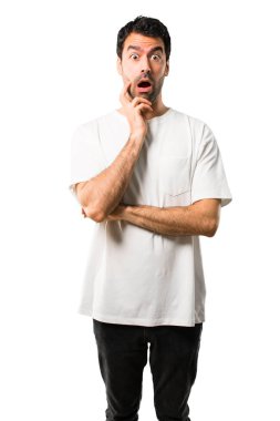 Şaşırttı ve doğru bakarken şok beyaz gömlek olan genç adam. Etkileyici yüz duygu izole beyaz arka plan üzerinde