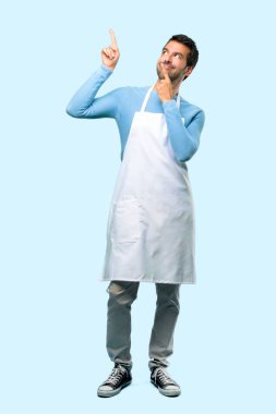Harika bir fikir işaret parmağı ile işaret ve mavi arka plan üzerinde ararken bir önlük giyen adamın tam vücut
