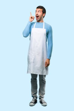 Çözüm için parmak üzerinde mavi arka plan kaldırma sırasında anlar bir önlük giyen adamın tam vücut