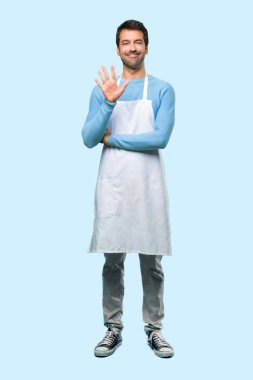 Beş parmak üzerinde mavi arka plan ile sayma bir önlük giyen adamın tam vücut