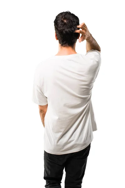 Young man with white shirt on back position looking back while scratching head on isolated white background