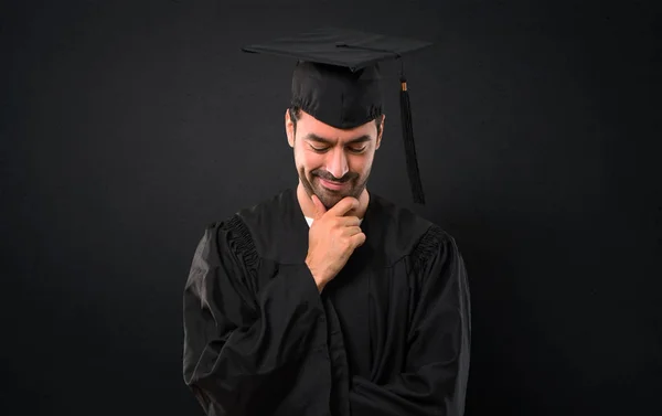 立っていると 黒い背景にあごに手を見下ろし卒業日大学の男 — ストック写真