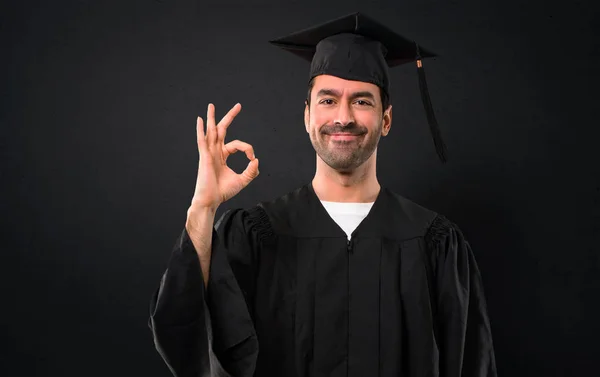 のサインを示す彼の卒業日大学の男 幸福と黒い背景に満足の顔 — ストック写真