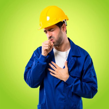 Kask ile genç işçi ile öksürük acı ve üzerinde yeşil arka plan kötü hissediyor