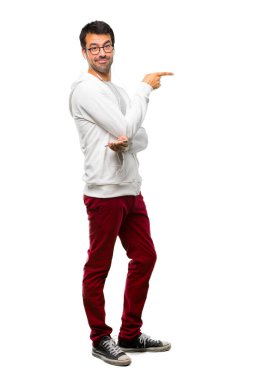 Bir adam gözlük ve parmak tarafına işaret ve beyaz arka planda lateral pozisyonda bir ürün sunan dinleme müzik tam uzunlukta bir kadeh