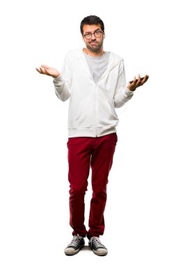 Gözlük ve müzik dinleme mutsuz ve bir şey ile sinirli olan bir adam tam uzunlukta bir kadeh çünkü bir şey anlamıyor. Beyaz arka plan üzerinde negatif yüz ifadesi